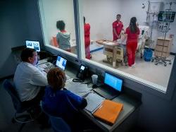 Nursing professor and faculty observing students in simulation lab.